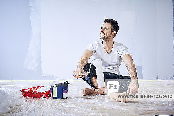 Smiling man sitting in new apartment taking a break from painting