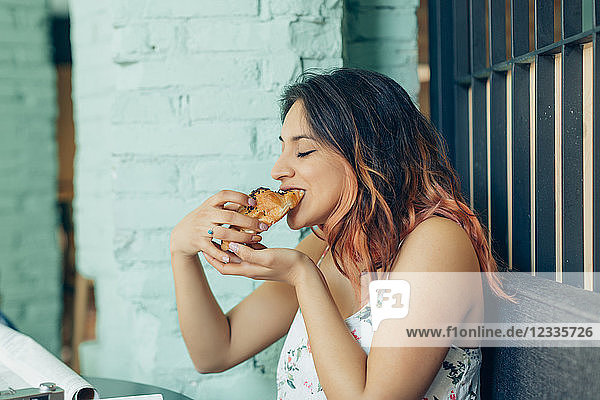 Woman eating croissant in coffee shop