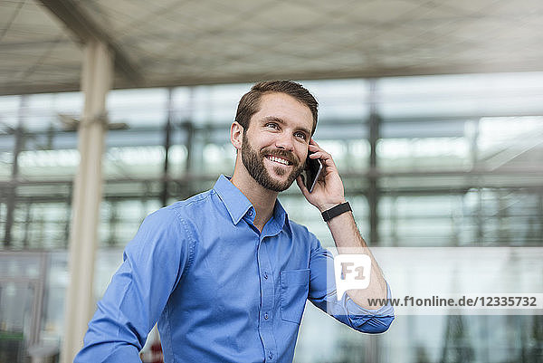 Smiling young businessman on cell phone outdoors