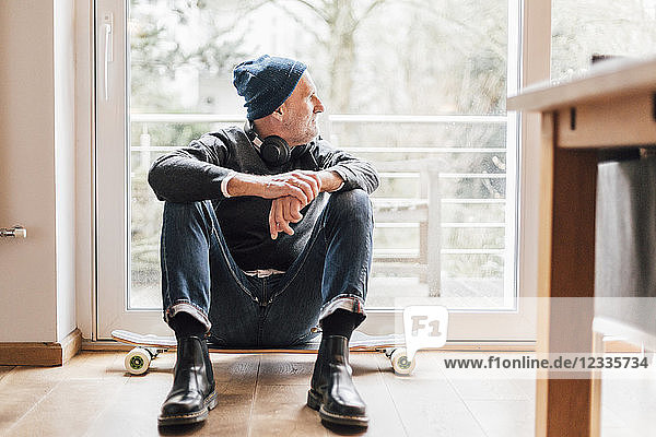 Cool senior man sitting on ground  looking out of window