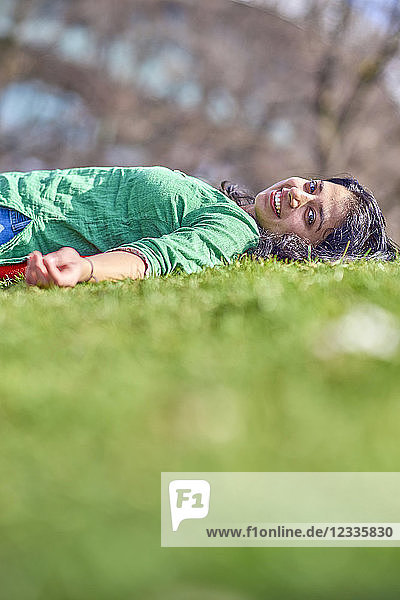 Portrait of happy young woman lying on meadow