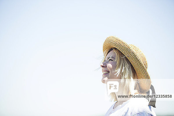 Young smiling woman with sun hat looking up  blue sky  copy space