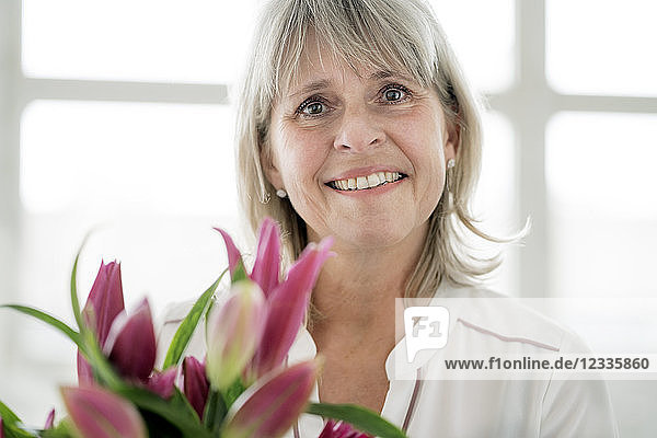Portrait of smiling mature woman holding bunch of flowers