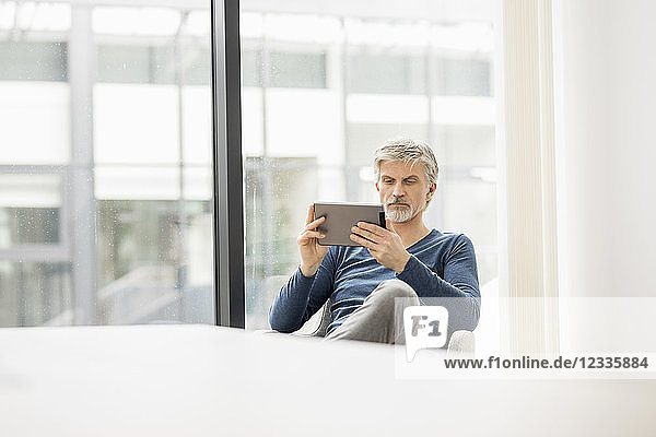 Mature man sitting in his office  using digital tablet