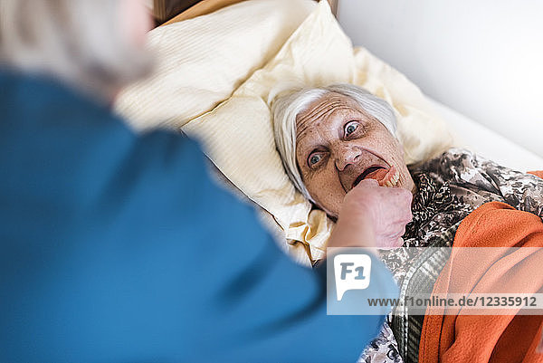Woman taking care of old woman lying in bed