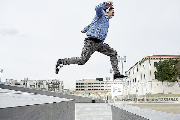 Young man jumping over gap between walls  mid air