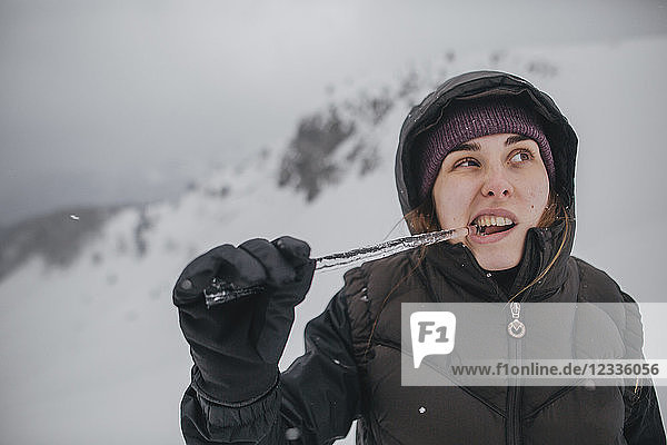 Austria  Kitzbuehel  portrait of young woman biting icicle