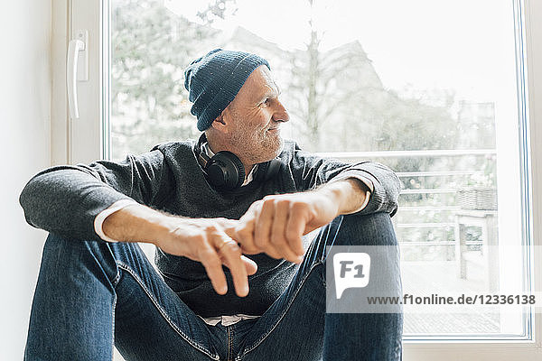 Cool senior man sitting on longboard  looking out of window