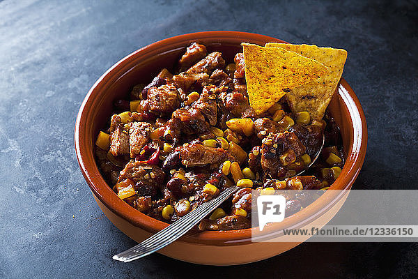 Vegetarian Chili with soy meat cut into strips and tortilla chips in earthenware dish
