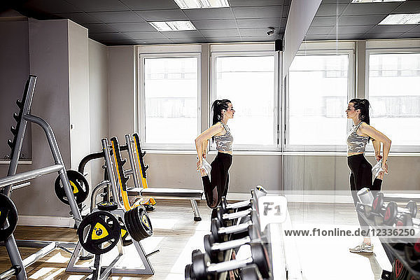 Woman exercising in gym looking in mirror