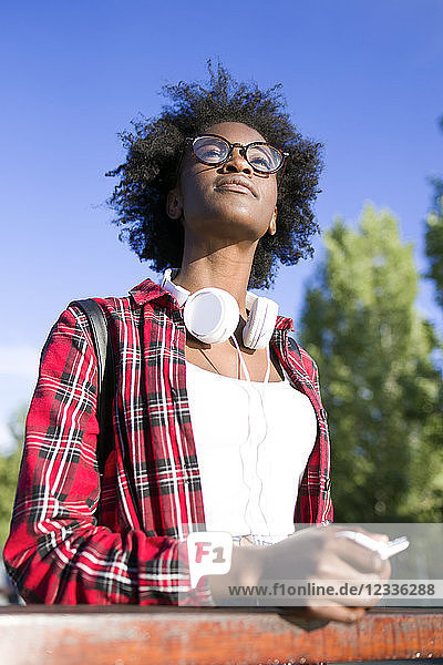 Portrait of young woman with headphones and cell phone