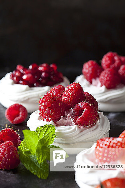 Meringue pastries garnished with whipped cream and raspberries