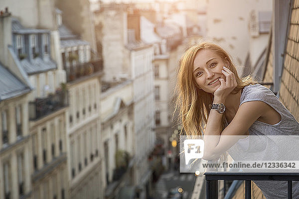 France  Paris  portrait of smiling woman standing on balcony in the evening