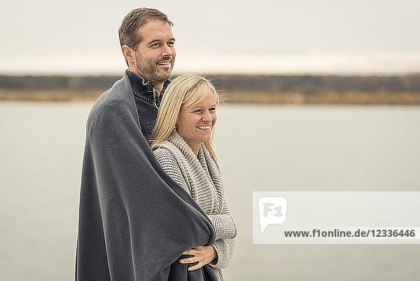 Happy couple standing at lake shore  embracing