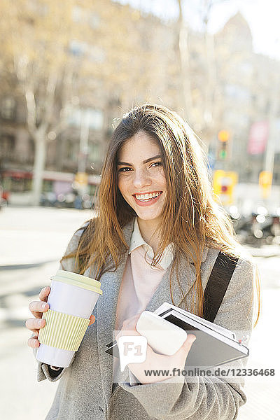 Spain  Barcelona  portrait of laughing young businesswoman with coffee to go