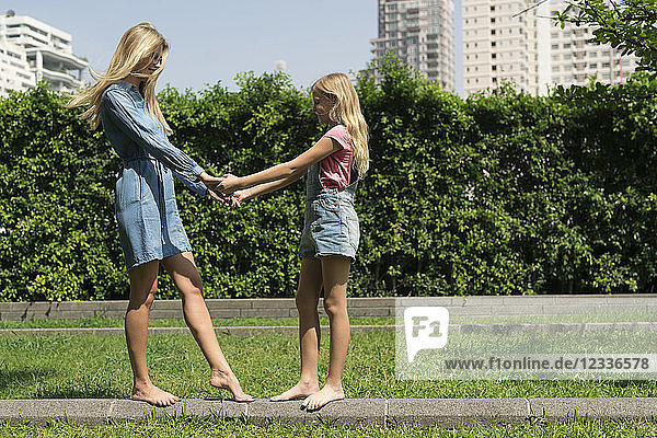 Happy mother and daughter holding hands in urban city garden