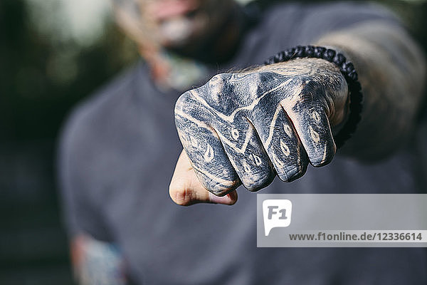 Close-up of clenched fist of tattooed young man outdoors