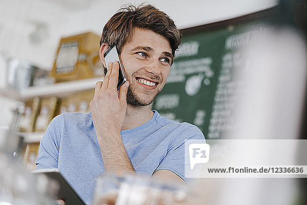 Smiling man in a cafe on cell phone