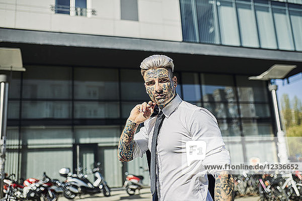 Young businessman with tattooed face walking in the city  portrait