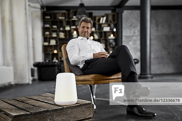 Mature man using voice-controlled digital assistant in loft