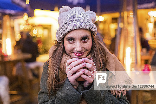 Portrait of content young woman drinking mulled wine at Christmas market
