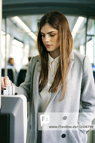 Portrait of young woman validating ticket in tramway