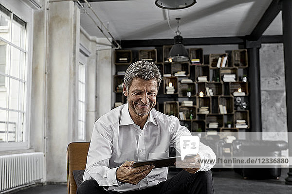 Smiling mature man using digital tablet in loft
