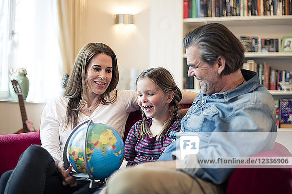 Happy family sitting on couch with globe