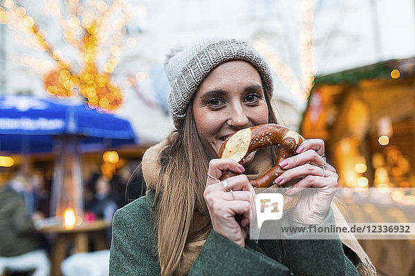 Portrait of smiling young woman with pretzel at Christmas market