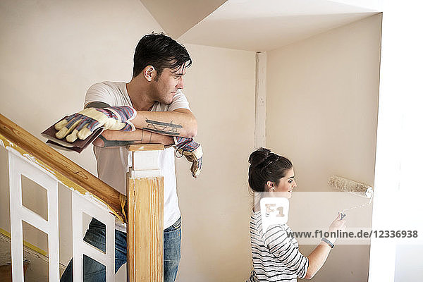 Young couple refurbishing new home  painting staircase