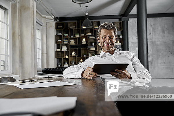 Smiling mature man using digital tablet in loft office