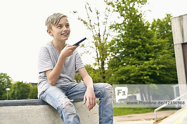 Boy recording voice message on smartphone
