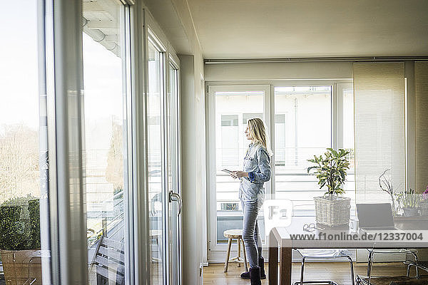 Woman with tablet looking out of window
