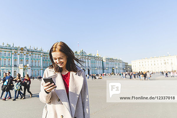Russia  St. Petersburg  young woman using smartphone in the city