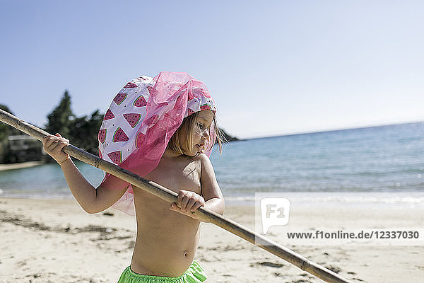 Little girl with stick playing on the beach