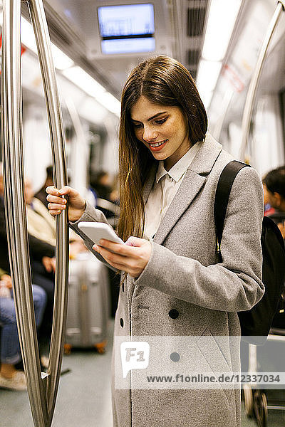 Spain  Barcelona  young businesswoman using cell phone in underground train