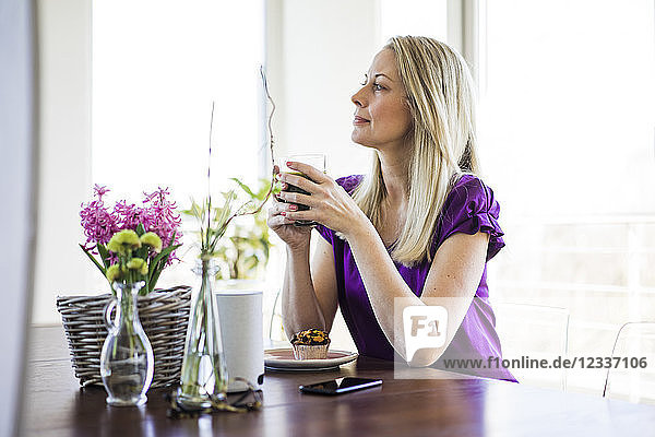 Mature woman sitting at table relaxing with glass of coffee