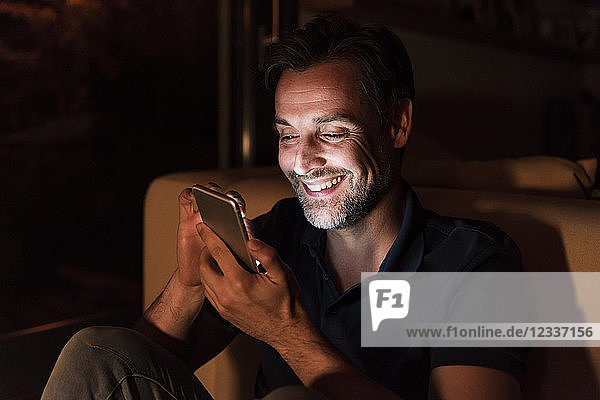 Portrait of happy mature man using cell phone at home