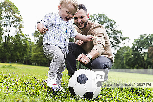 Happy father playing football with son in a park