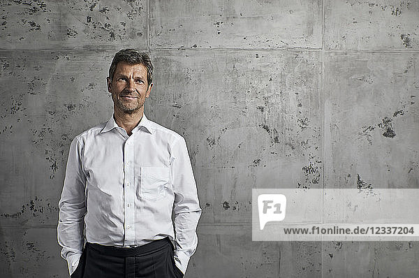 Portrait of smiling mature man in front of concrete wall