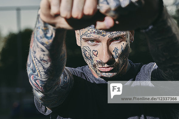 Portrait of tattooed young man outdoors clenching his fists