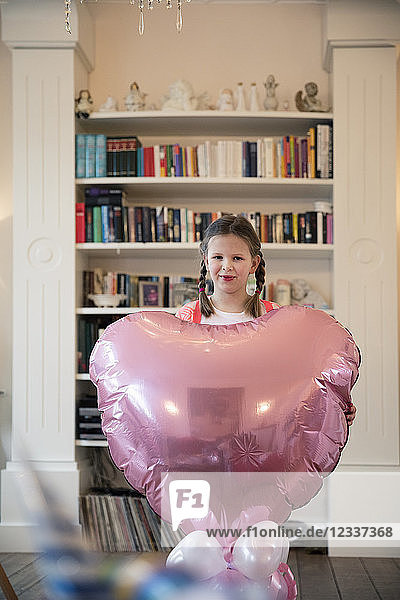 Portrait of girl with braids holding big heart-shaped balloon
