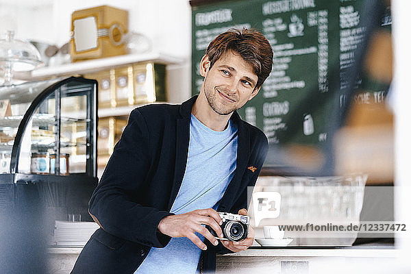 Smiling man in a cafe holding camera