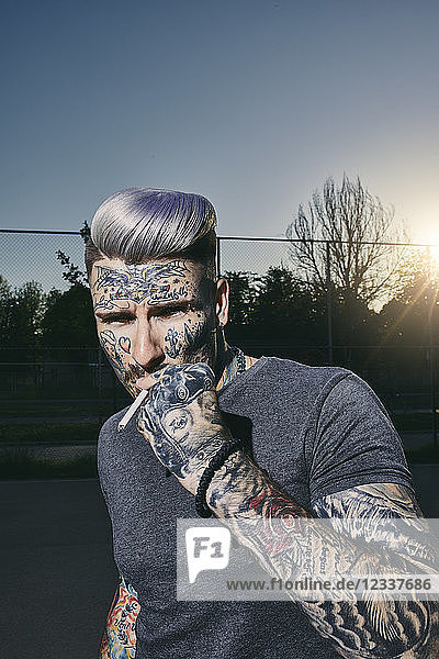 Portrait of tattooed young man smoking a cigarette