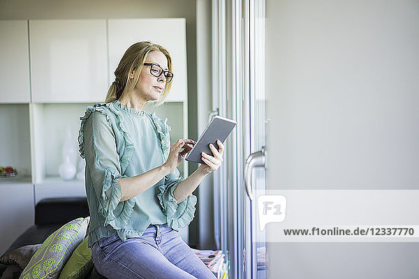 Mature woman sitting on couch using tablet