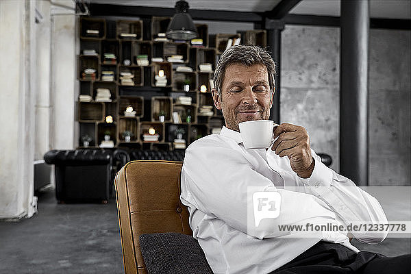 Portrait of mature man enjoying cup of coffee in loft