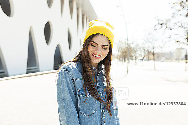 Spain  Barcalona  portrait of laughing young woman wearing yellow cap