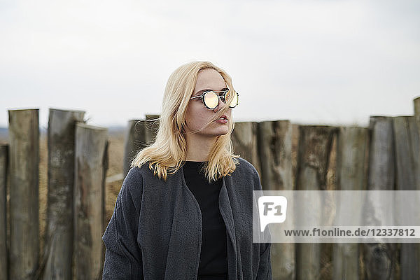 Portrait of blond young woman wearing mirrored sunglasses on the beach