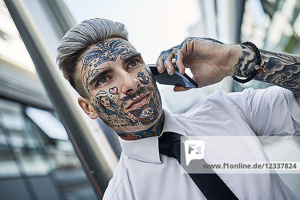 Young businessman with tattooed face  talking on he phone