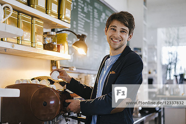 Portrait of smiling man in a cafe holding cup